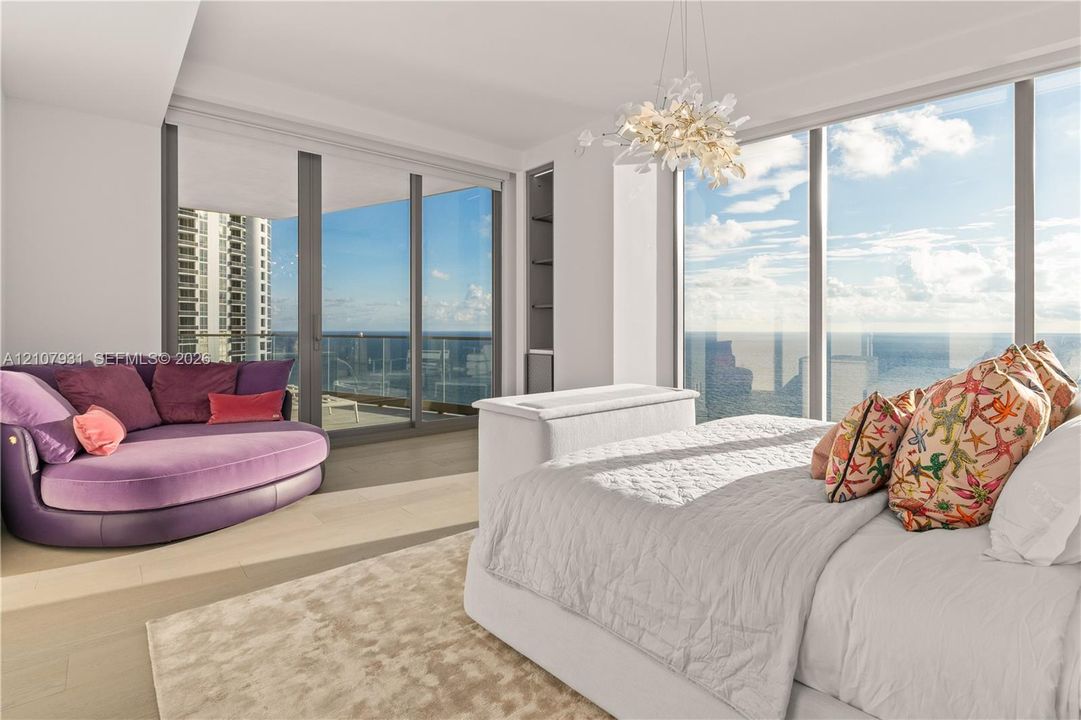 Floor-to-ceiling glass windows, recessed display shelving, wood-finish flooring, integrated ceiling light fixture, and sliding glass doors opening to a balcony