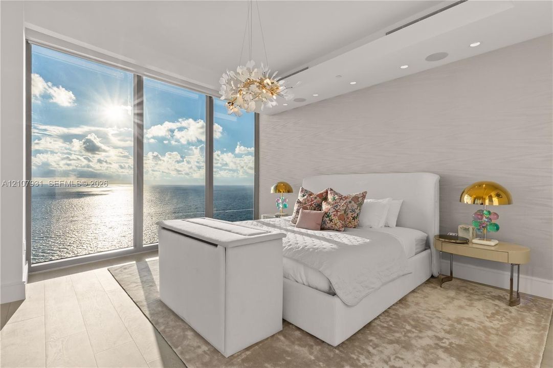 Floor-to-ceiling windows featuring ocean scenery, wood-finish flooring, recessed lighting, and a textured wall finish