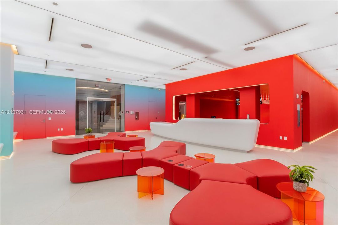 Contemporary lobby featuring a sculpted white built-in reception desk, high-gloss solid flooring, recessed linear lighting, and gradient-finished walls