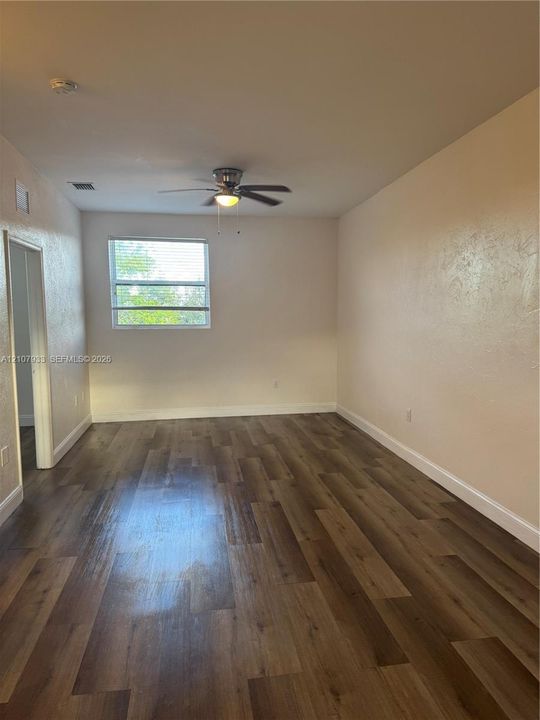 Interior space featuring wood-finish flooring, a neutral wall palette, and a central ceiling fan with an integrated light fixture