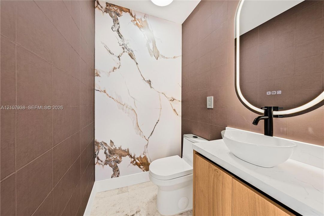 Modern vanity featuring wood-finish cabinetry, a white countertop, and a vessel sink with a matte black faucet