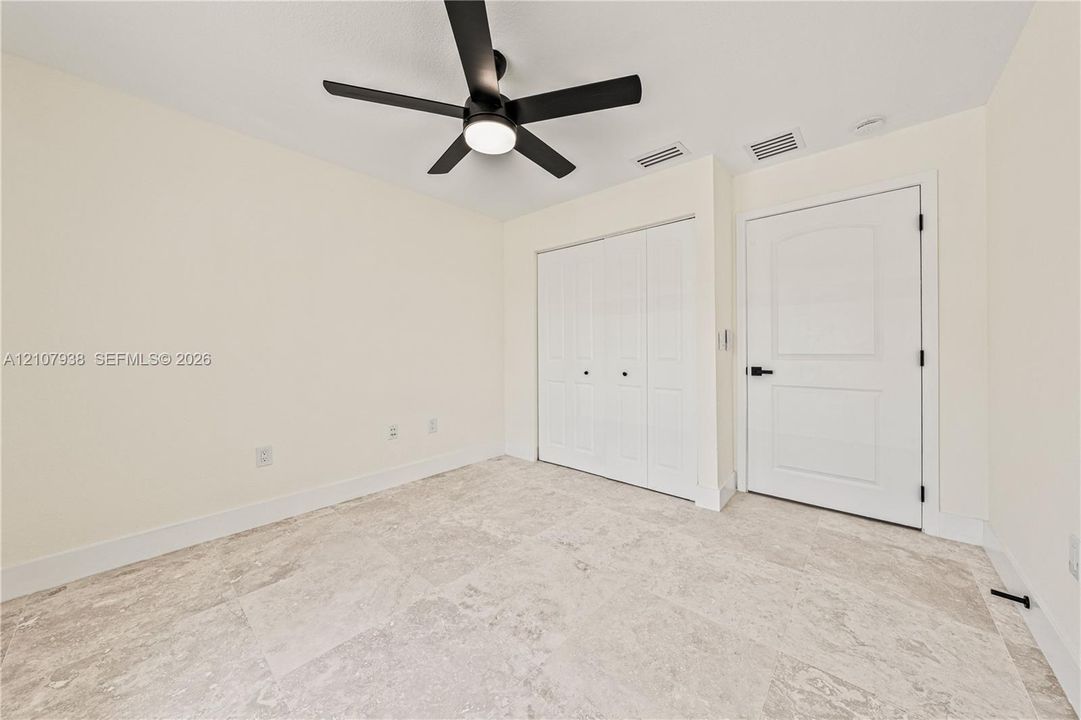 Neutral-toned flooring, matte black ceiling fan with integrated lighting, and white interior door featuring matte black hardware