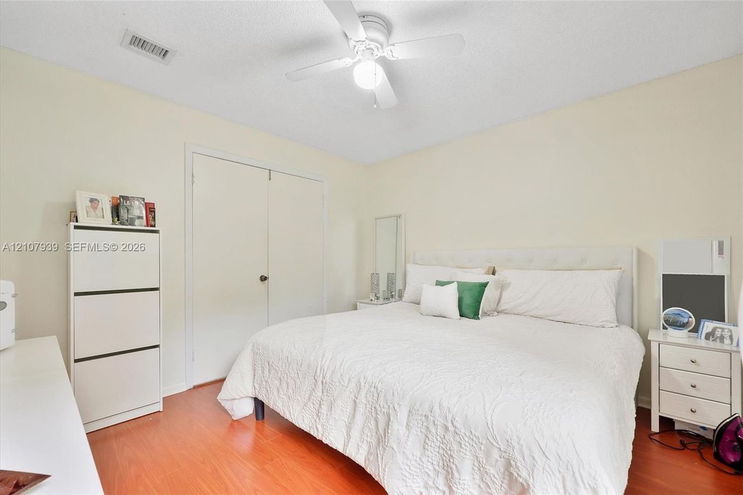 Room featuring wood-finish flooring, a ceiling-mounted light fixture with a fan, and a double-door closet