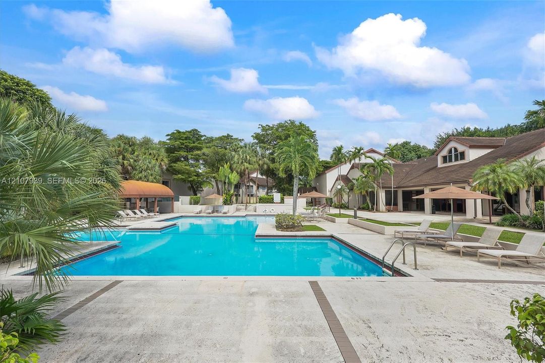 Swimming pool with stone-tiled decking, integrated landscaping, and surrounding structures