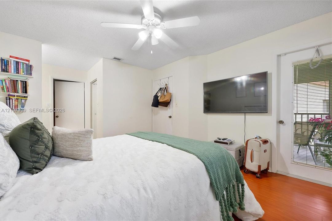 Wood-finish flooring, ceiling fan with integrated lighting, and glass-paneled door with exterior access