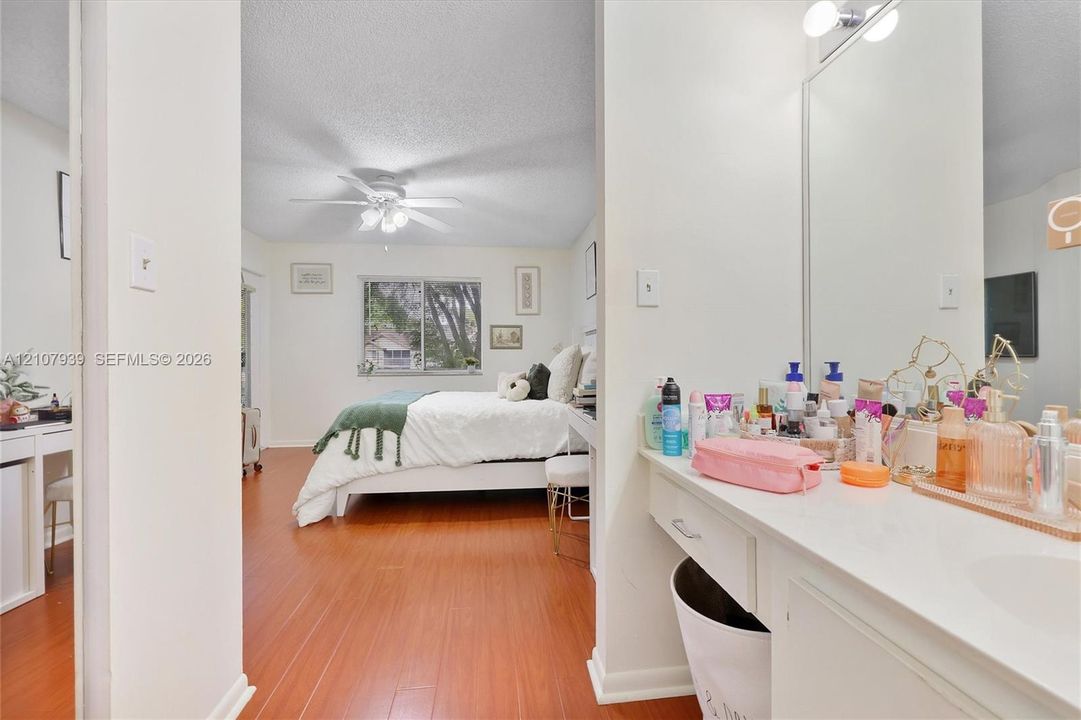 Bathroom featuring a vanity with a white countertop and integrated sink, accompanied by an expansive wall-mounted mirror and overhead lighting