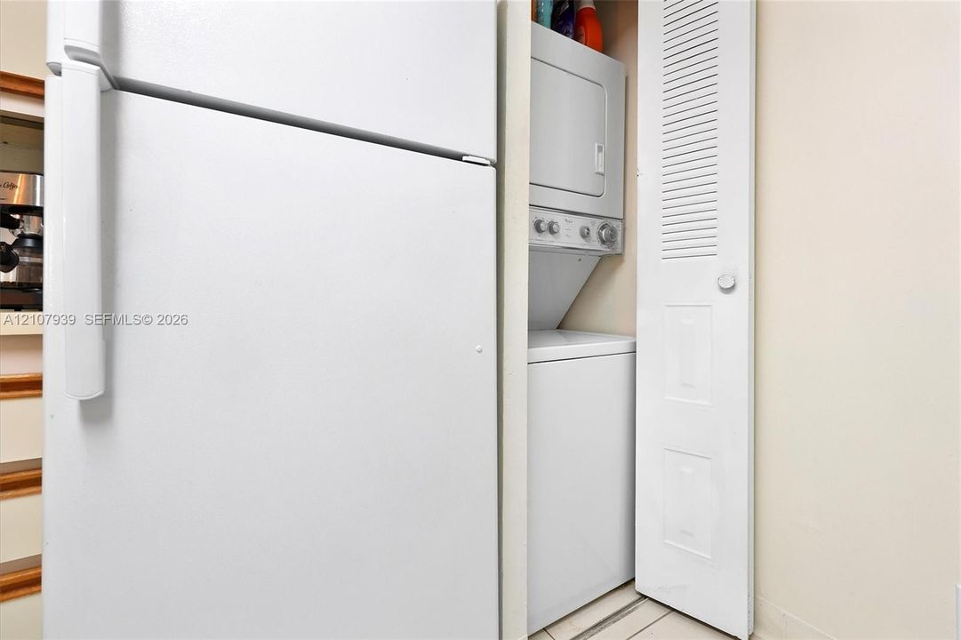 Built-in stacked laundry unit with louvered bi-fold door and full-size refrigerator