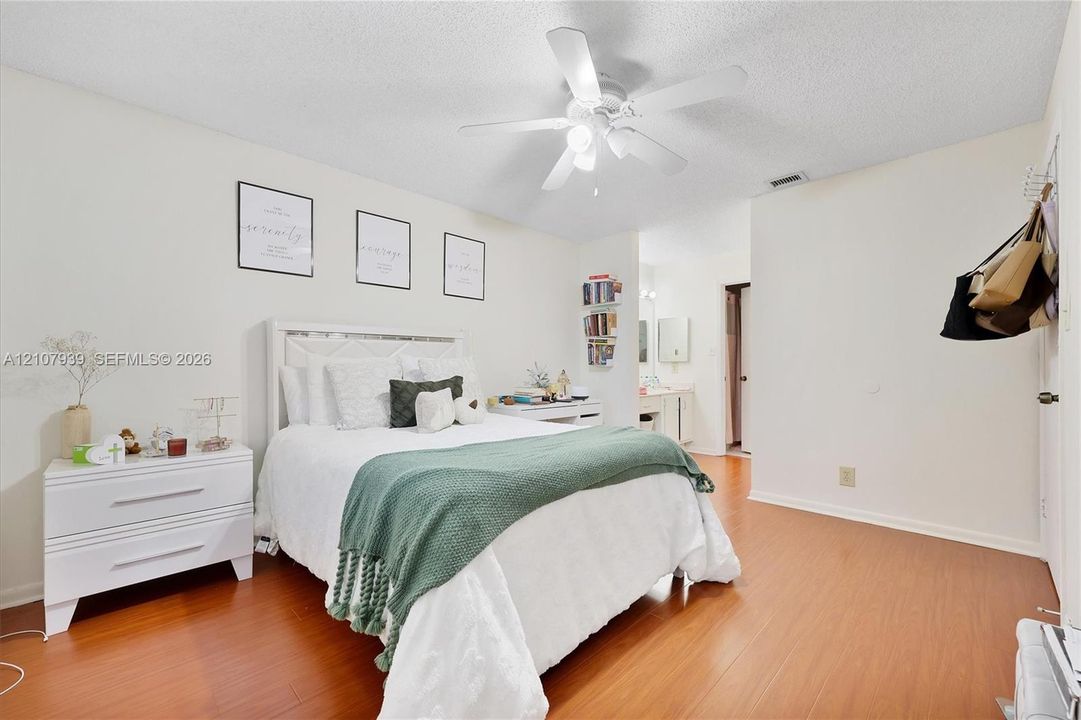 Neutral-toned interior featuring wood-finish flooring, a ceiling-mounted light fixture with fan, and a textured ceiling
