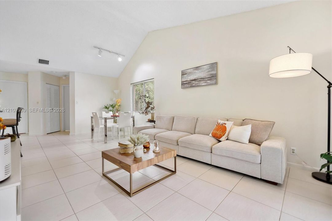 Living area featuring vaulted ceilings, large-format tile flooring, and adjustable track lighting