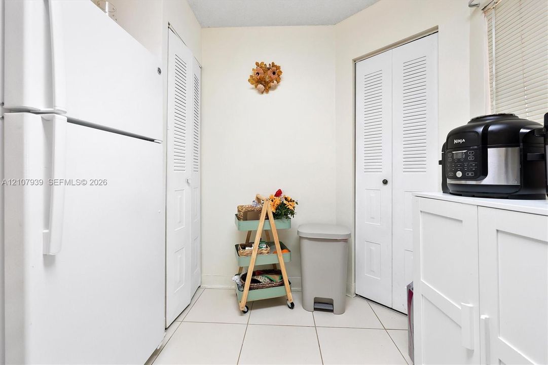 Tile flooring, two sets of white louvered-panel closets, and white cabinetry