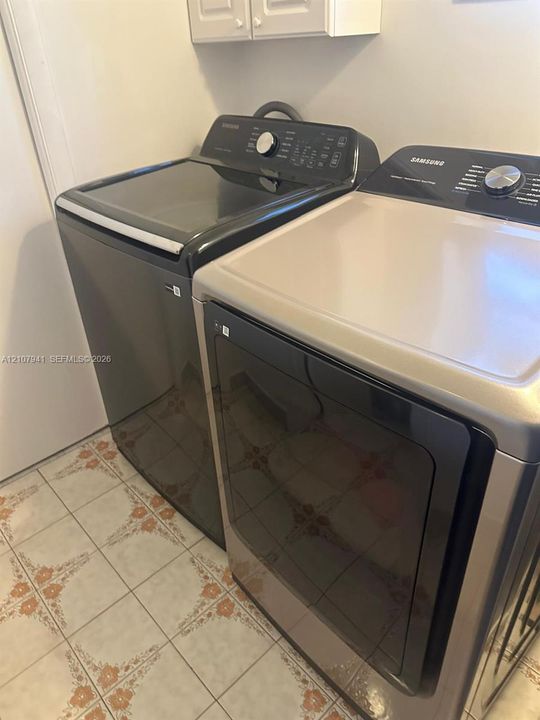 Dedicated laundry area featuring patterned ceramic tile flooring and wall-mounted cabinetry
