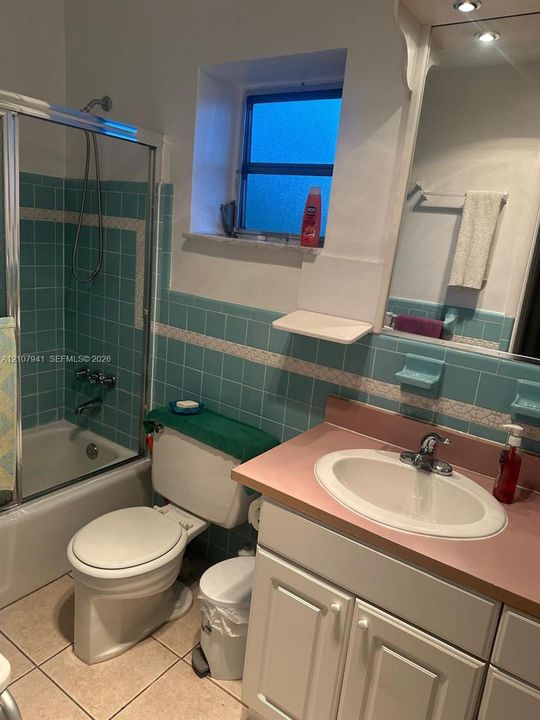 Bathroom featuring white cabinetry, a solid-surface vanity countertop with an integrated oval sink, chrome faucet fixtures, and tile wainscoting with decorative inlay