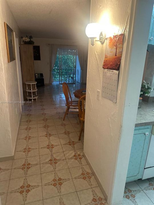 Interior space featuring patterned tile flooring, wall-mounted globe lighting, and a glass sliding door