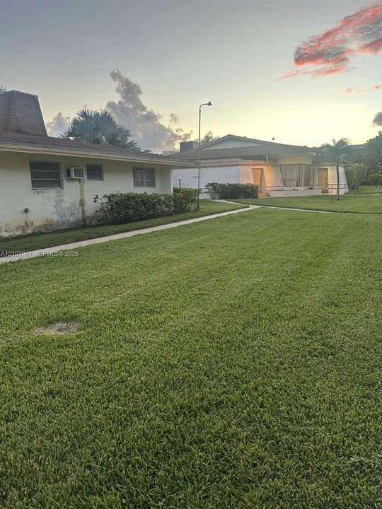 Extensive green space featuring mature palm trees, concrete walkways, and low-profile buildings with stucco exteriors