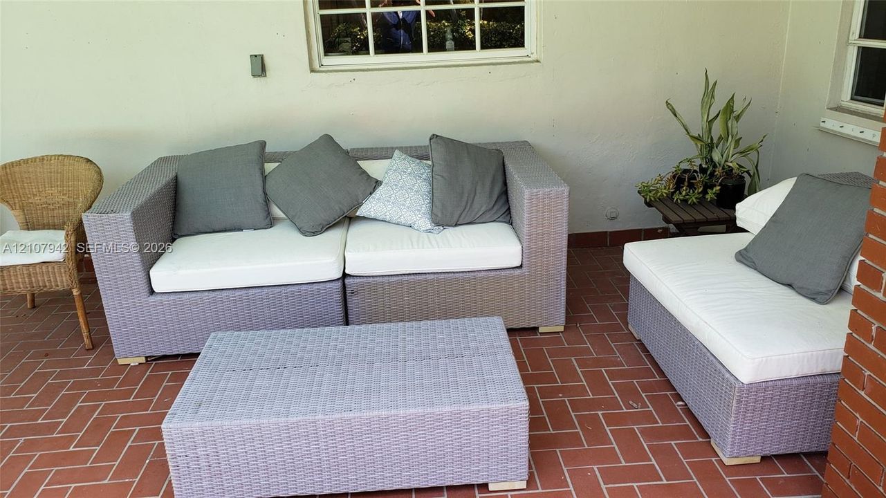 Covered outdoor space featuring red brick flooring in a herringbone pattern and an exposed red brick exterior pillar