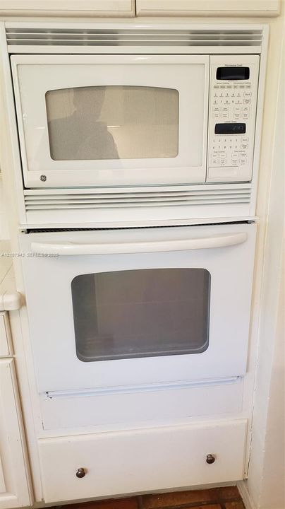 Built-in white microwave and oven unit featuring a digital control panel, integrated ventilation, and lower storage drawer