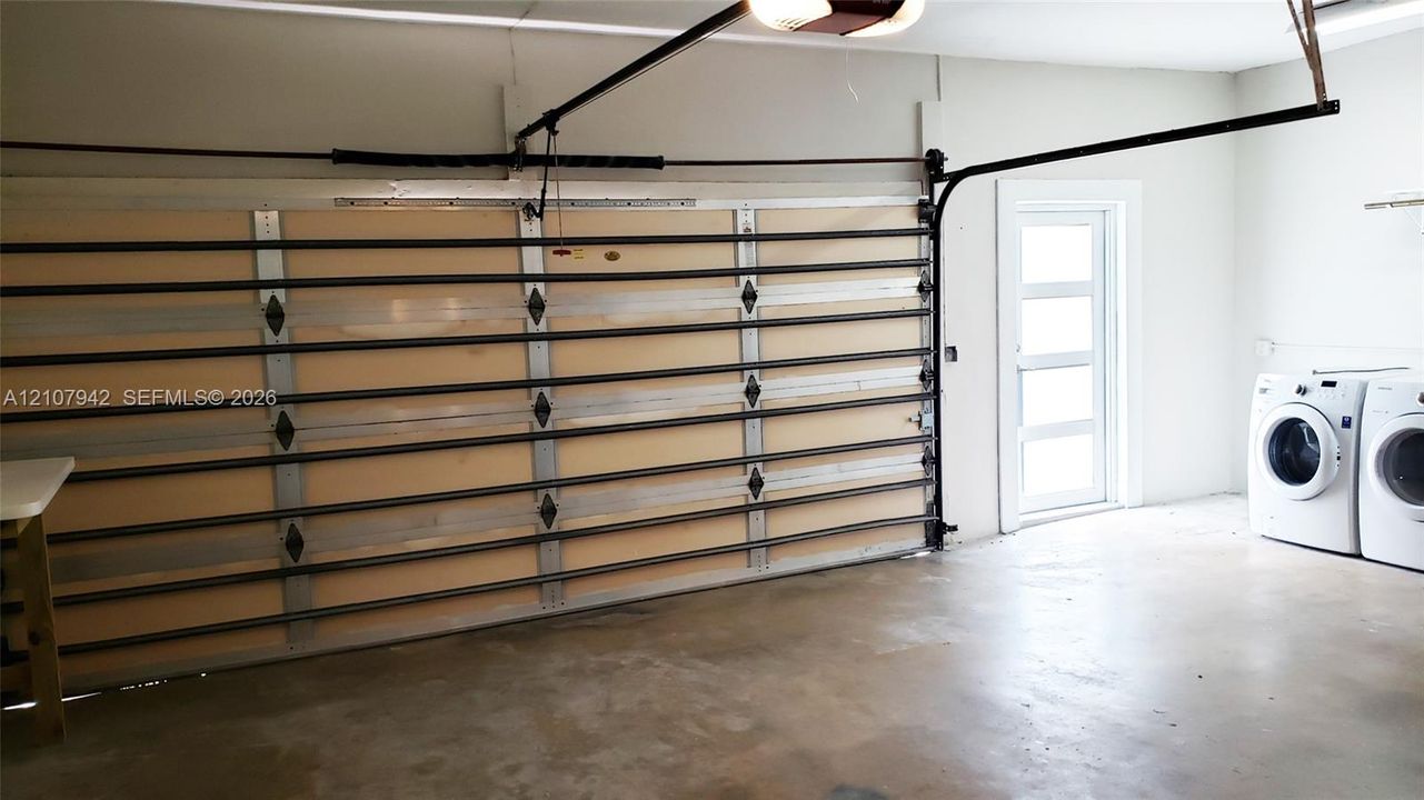 Garage featuring a multi-panel door, concrete flooring, and a dedicated laundry area with side-by-side washer and dryer