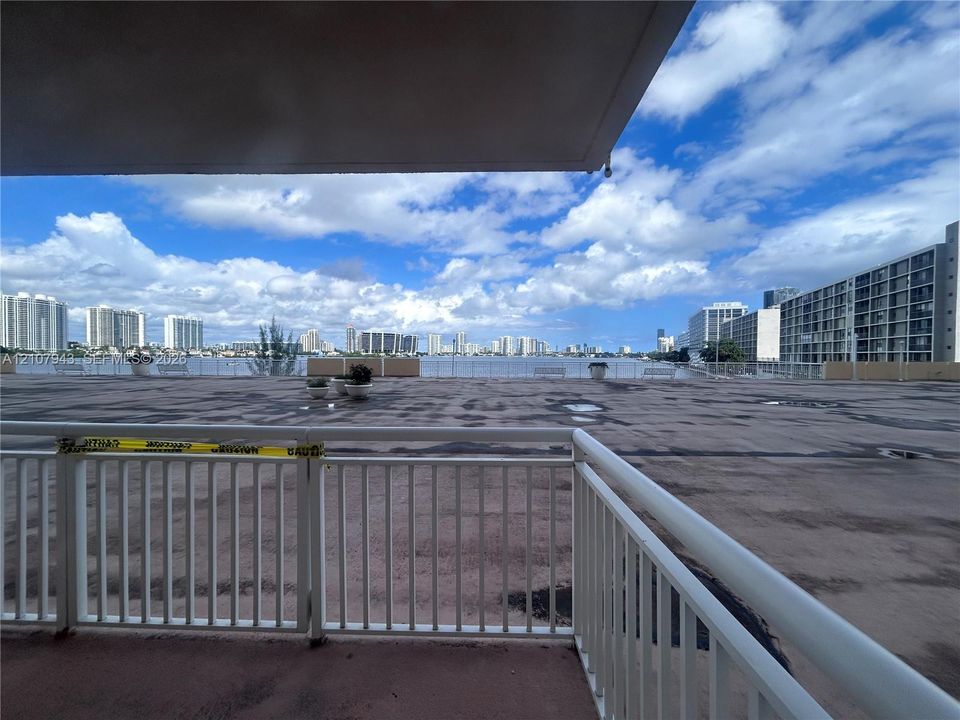 Expansive open-air terrace featuring a white metal railing and direct water and city skyline exposure