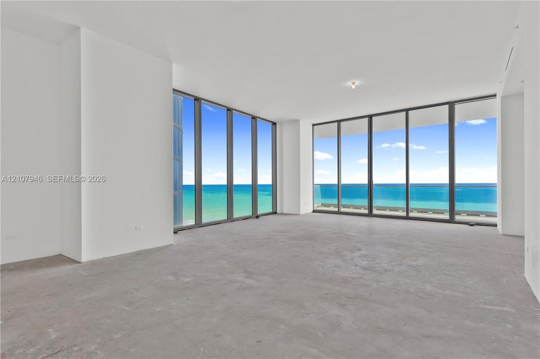 Expansive floor-to-ceiling windows featuring dark-toned frames, providing unobstructed exposure to the ocean and horizon