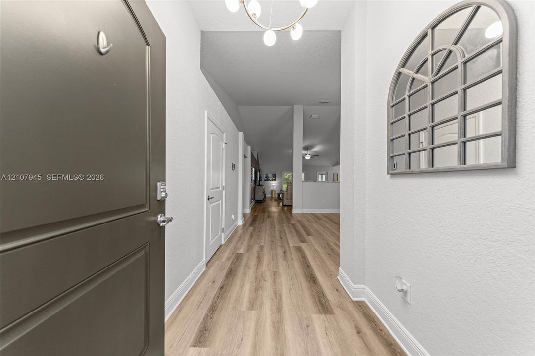 Entryway featuring wood-finish flooring, a multi-light chandelier, and a solid panel door