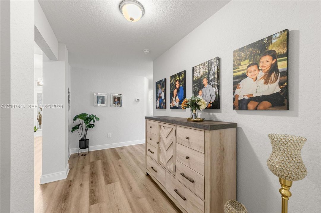 Interior hallway featuring wood-finish flooring, crisp neutral wall paint, and a ceiling-mounted light fixture