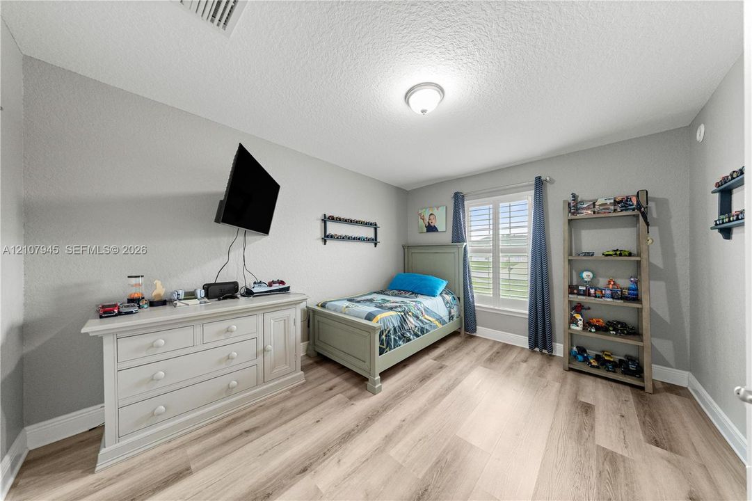 Room featuring neutral-toned walls, wood-finish flooring, and a single window with plantation shutters
