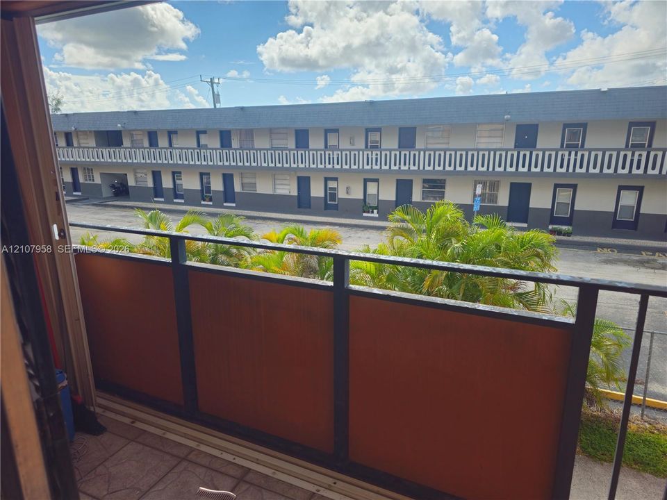 Balcony featuring metal railing with integrated opaque panels and paved flooring