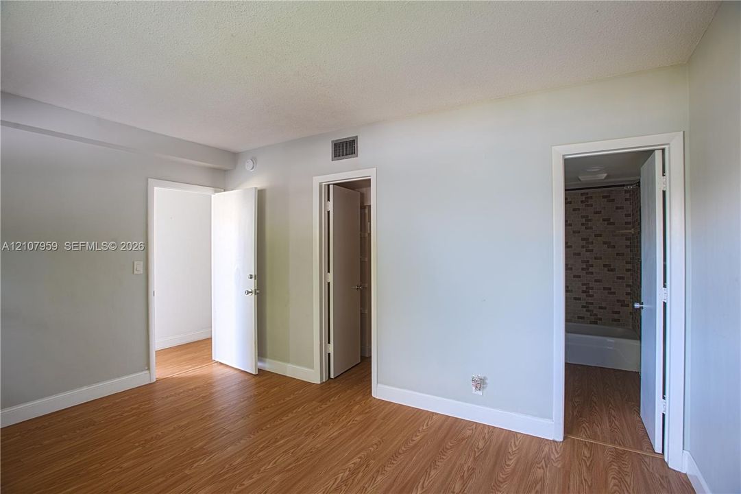 Wood-finish flooring, neutral wall tones, and doorways featuring interior slab doors