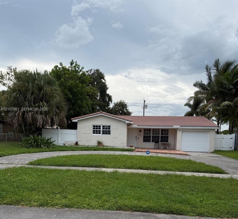 Single-story residence featuring a tile roof, stucco exterior, attached garage, and white vinyl privacy fencing