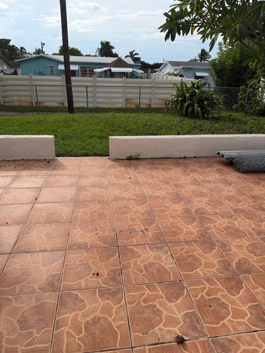 Tiled patio featuring a low masonry retaining wall and an open lawn area