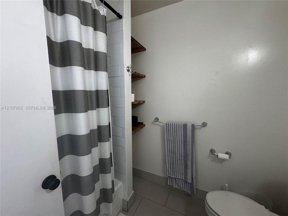 Bathroom featuring tile surround, built-in wooden shelving, and chrome hardware