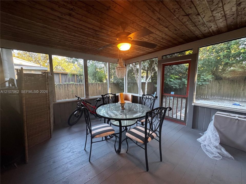 Screened-in porch featuring a wood-plank ceiling, stained wood-finish flooring, full-height insect screens, and a ceiling fan