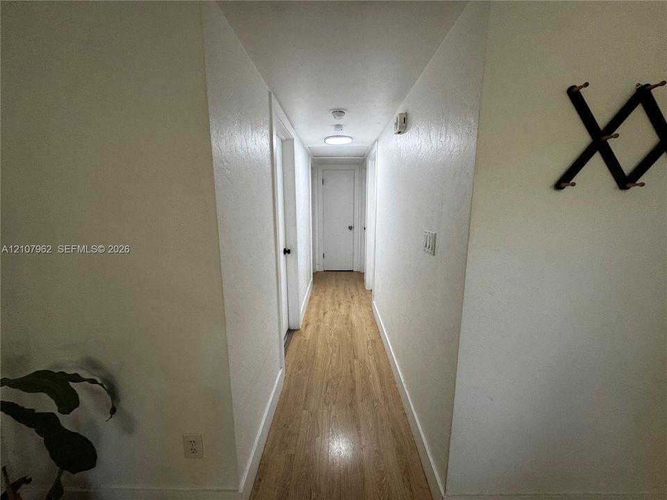 Hallway featuring wood-finish flooring, smooth-finish walls, and a flush-mount overhead light fixture