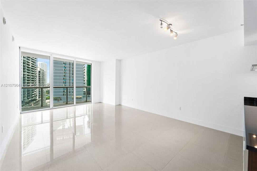 Open-concept interior featuring large-format tile flooring, floor-to-ceiling glass sliding doors, and multi-bulb track lighting
