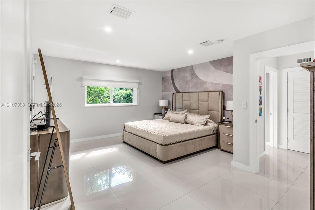 Spacious room featuring polished tile flooring, recessed lighting, and a large-format textured accent wall