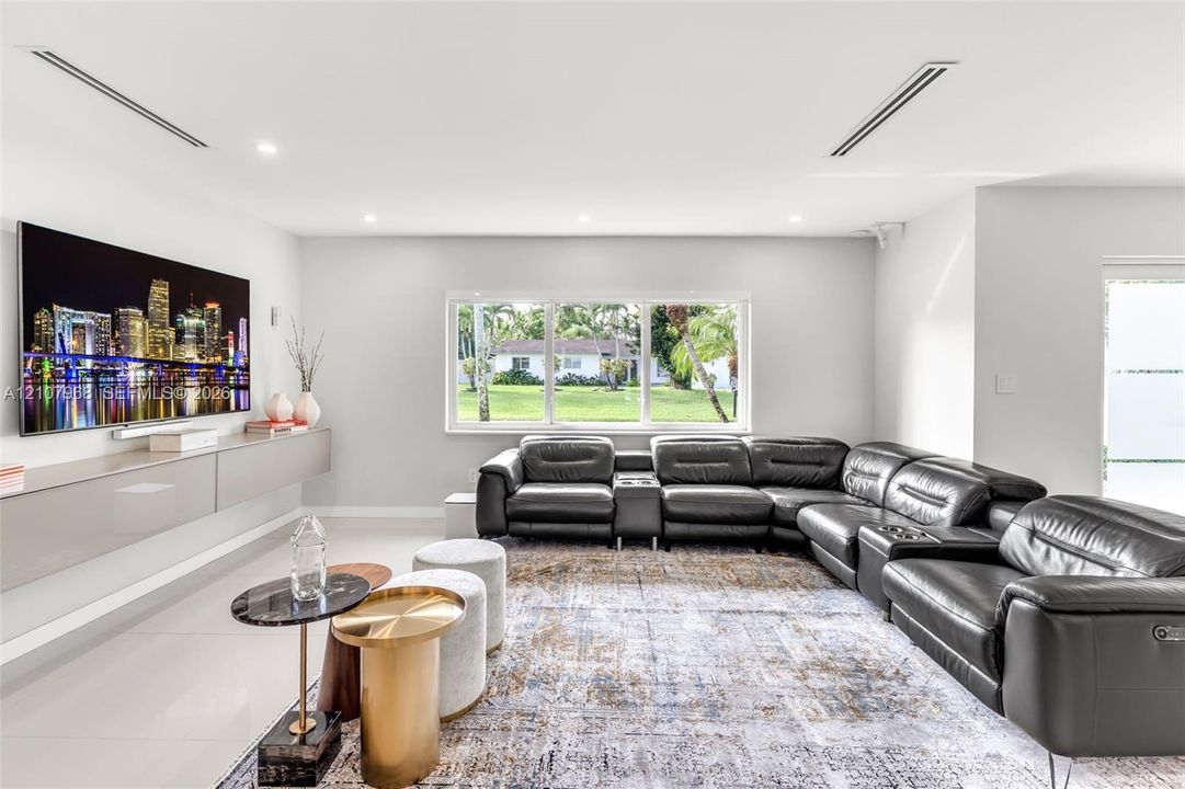 Living area featuring large-format tile flooring, recessed ceiling lighting, and a wall-mounted floating cabinetry unit