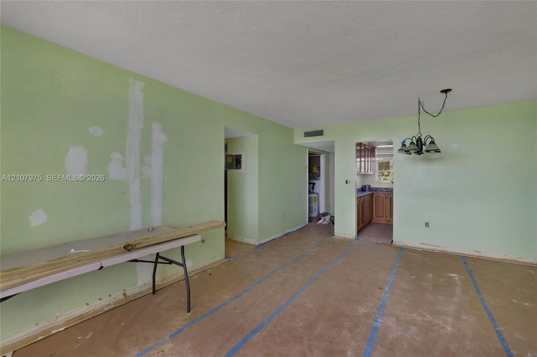 Interior space featuring a multi-arm hanging light fixture and access to an enclosed kitchen area