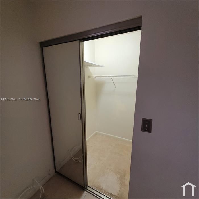 Closet featuring sliding mirror doors, metal wire shelving, and tile flooring