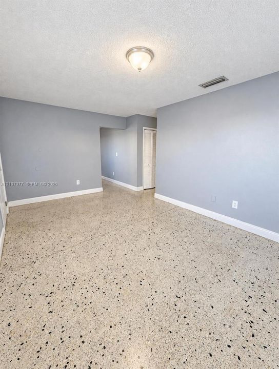 Interior space featuring neutral wall paint, polished stone flooring, a central flush-mount ceiling light fixture, and a built-in closet with folding doors