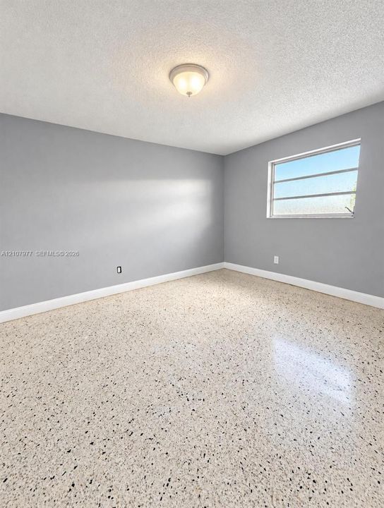Interior room featuring polished terrazzo flooring, neutral grey wall paint, and a central flush-mount dome light fixture