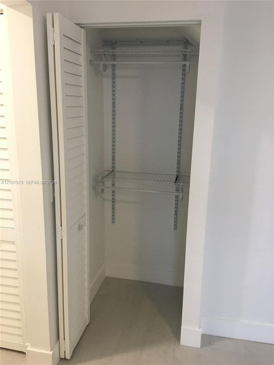 Closet featuring white louvered bi-fold doors and integrated wire shelving with adjustable wall-mounted tracks