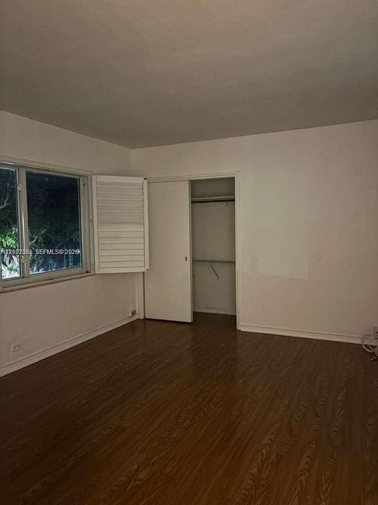 Wood-finish flooring, white plantation shutters, and a reach-in closet with sliding doors