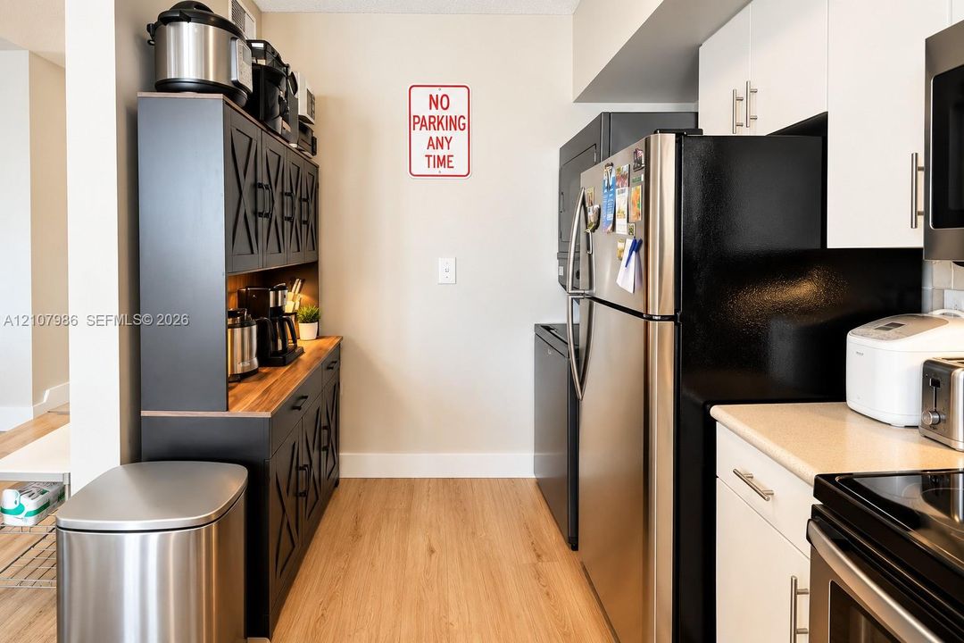 Kitchen featuring matte black built-in cabinetry with X-pattern detailing, wood-finish countertops, stainless steel appliances, and white flat-panel upper cabinetry