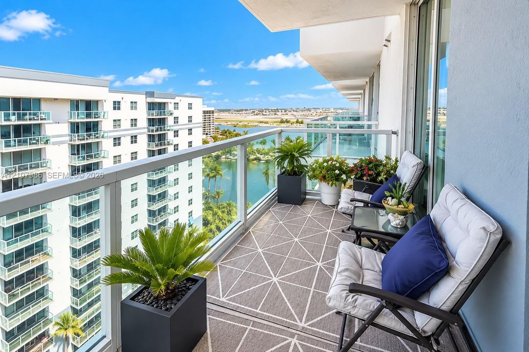 Covered balcony featuring a glass panel railing, concrete flooring, and water scenery