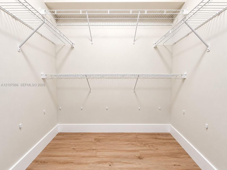 Storage area featuring wood-finish flooring and tiered white wire shelving