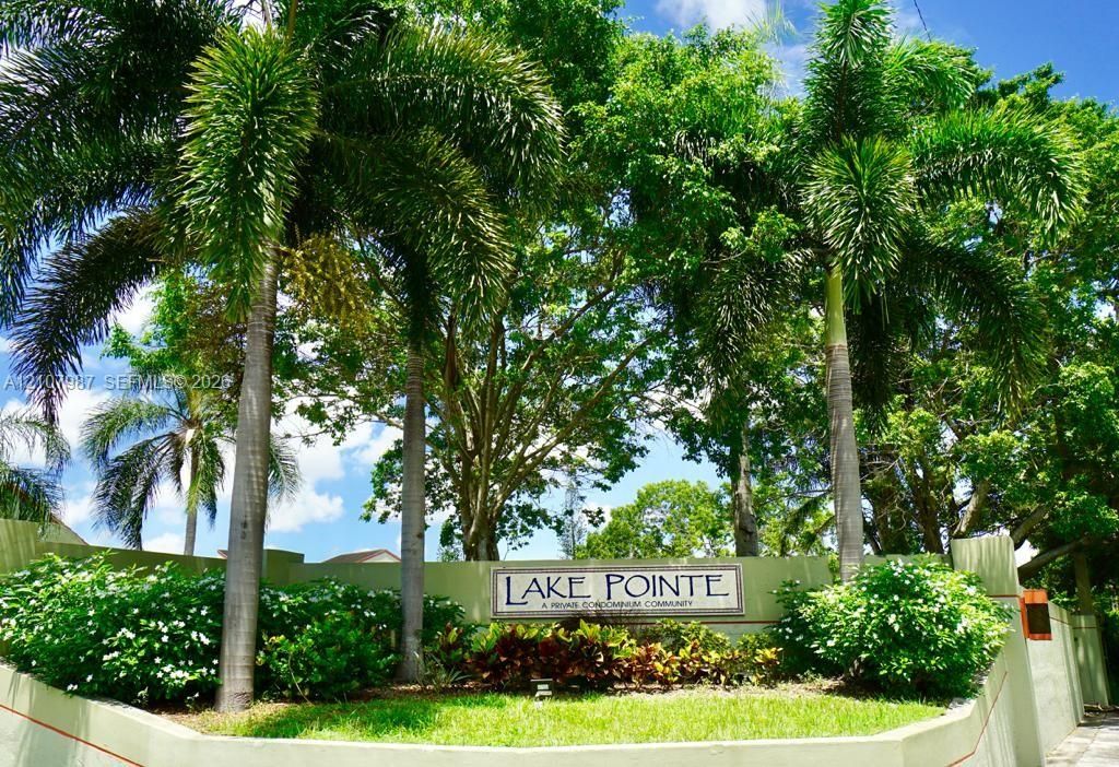 Community monument sign featuring professional landscaping, mature palm trees, and established greenery