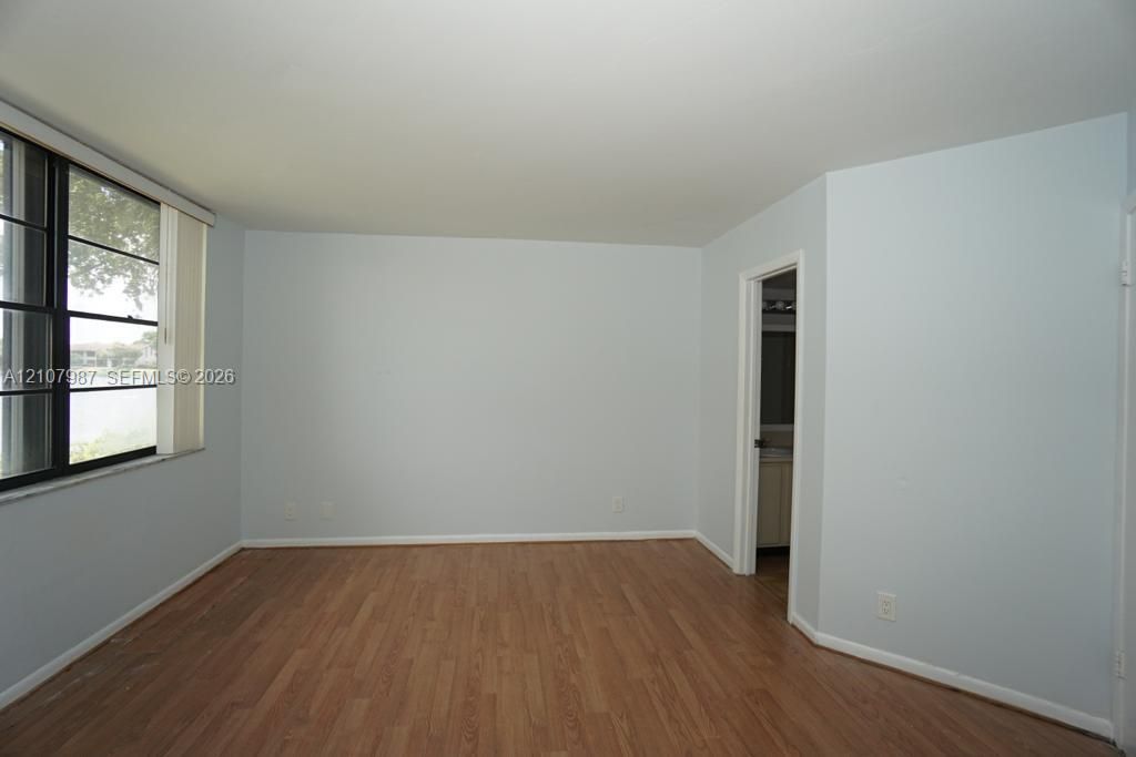 Wood-finish flooring, multi-pane window with dark framing, and neutral wall color