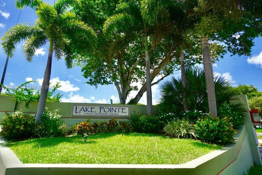 Monument signage featuring integrated landscaping, mature palm trees, and manicured lawn