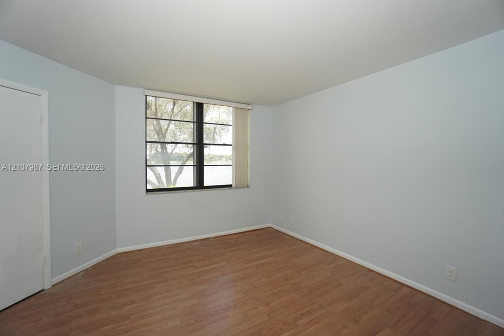 Neutral-toned interior space featuring wood-finish flooring, multi-pane windows, and a swinging interior door