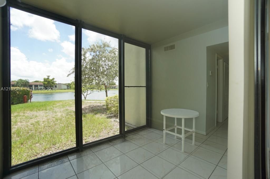 Enclosed porch featuring large floor-to-ceiling windows, light-toned ceramic tile flooring, and direct exposure to exterior water frontage